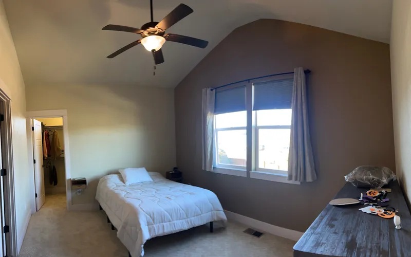 Bedroom with brown accent wall and vaulted ceiling