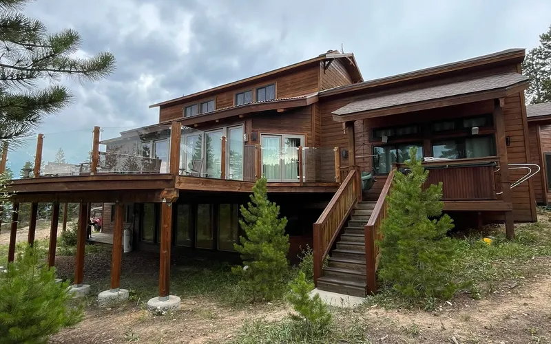 Mountain cabin exterior with stained wood and glass railing deck