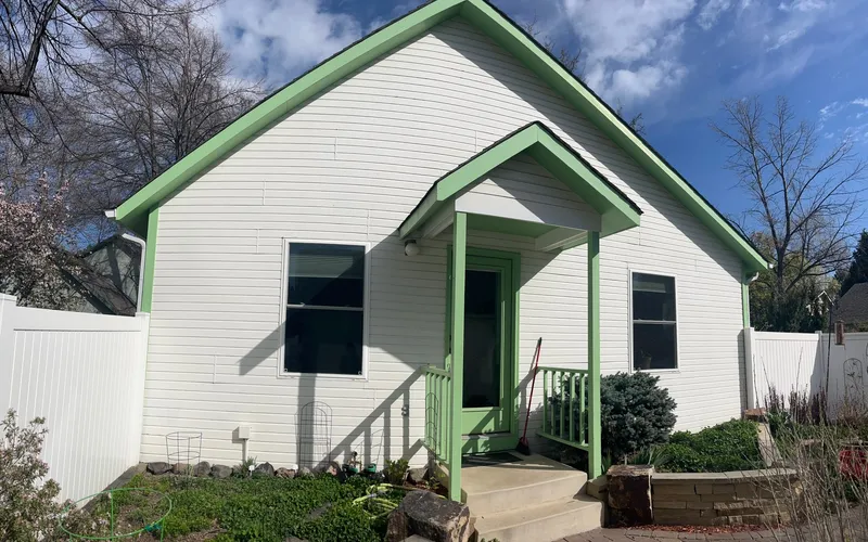 White cottage exterior with green trim and covered front porch